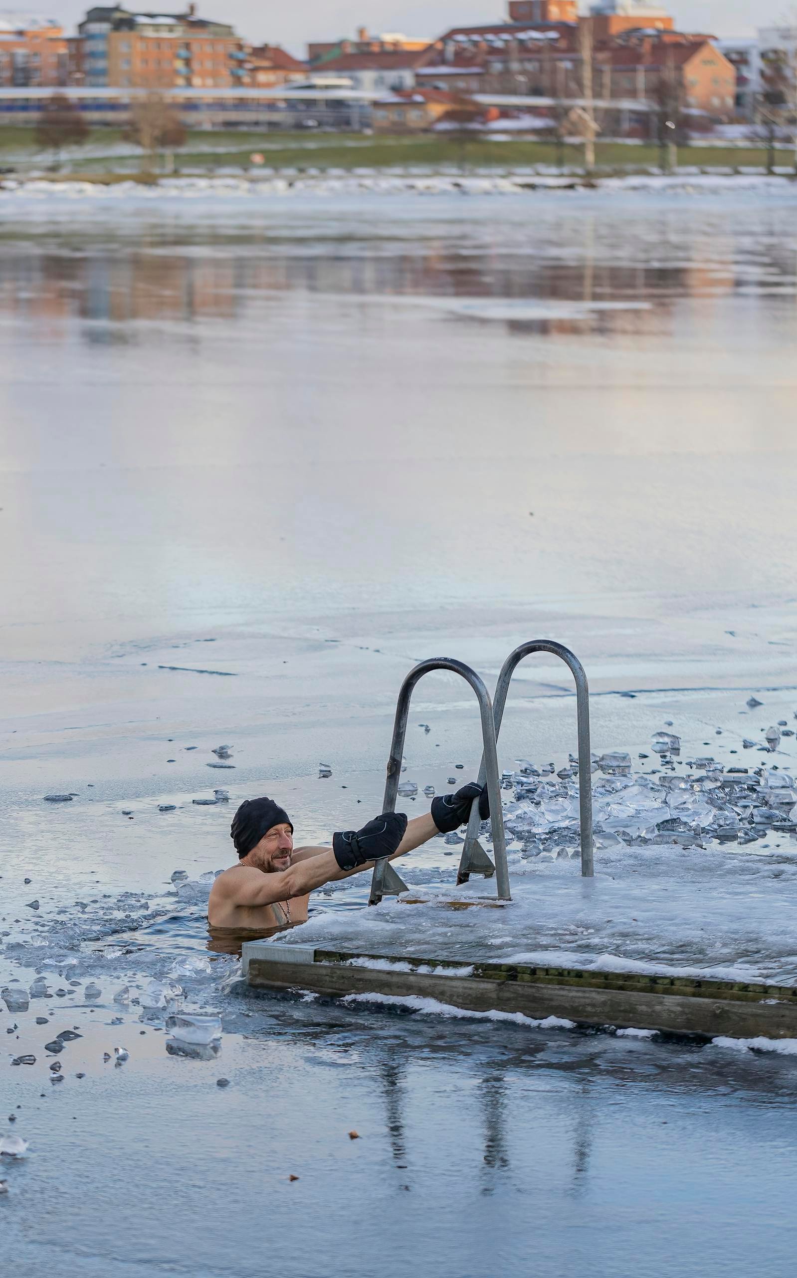 Man taking a daring swim in a frozen lake, surrounded by ice, showcasing winter resilience.